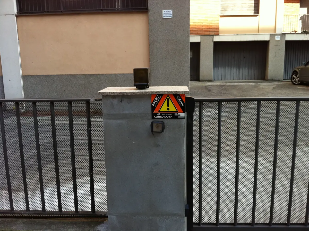 Lampeggiante e cartello di sicurezza sul pilastro di un cancello scorrevole automatico