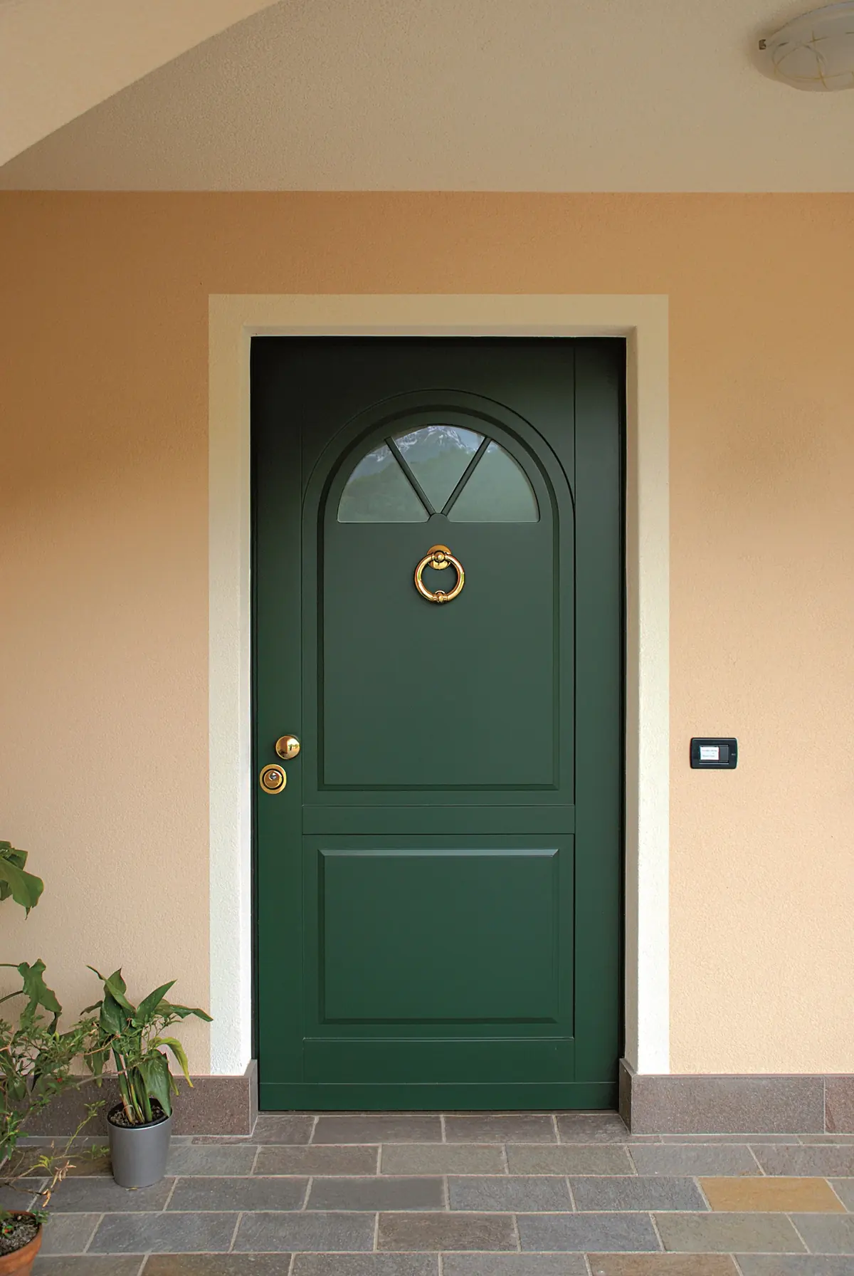 Porta blindata da esterno verde con sopraluce ad arco e battente in ottone