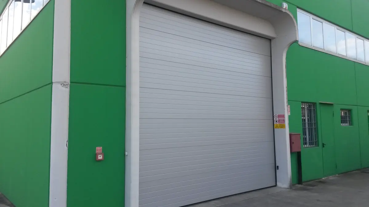 Portone sezionale industriale grigio su un capannone