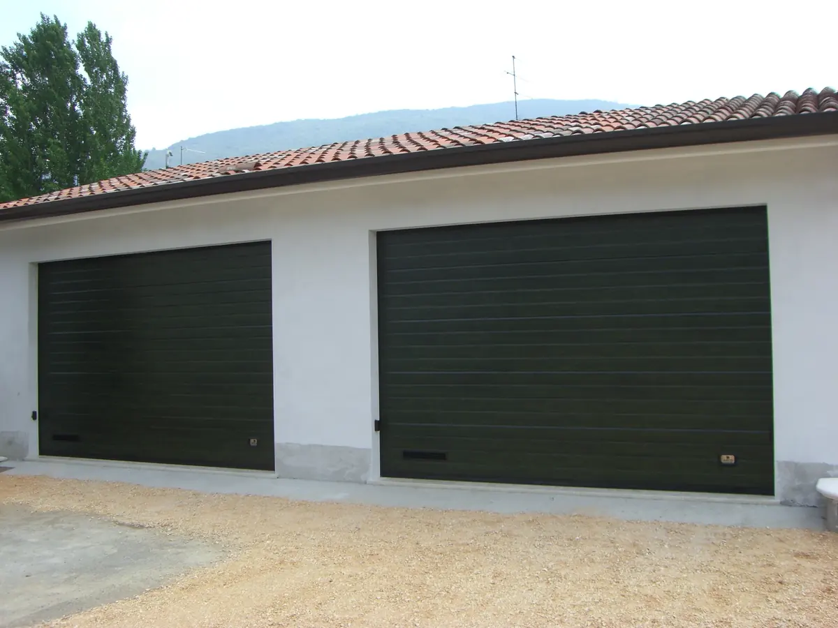 Coppia di portoni sezionali verde scuro su una casa con garage doppio