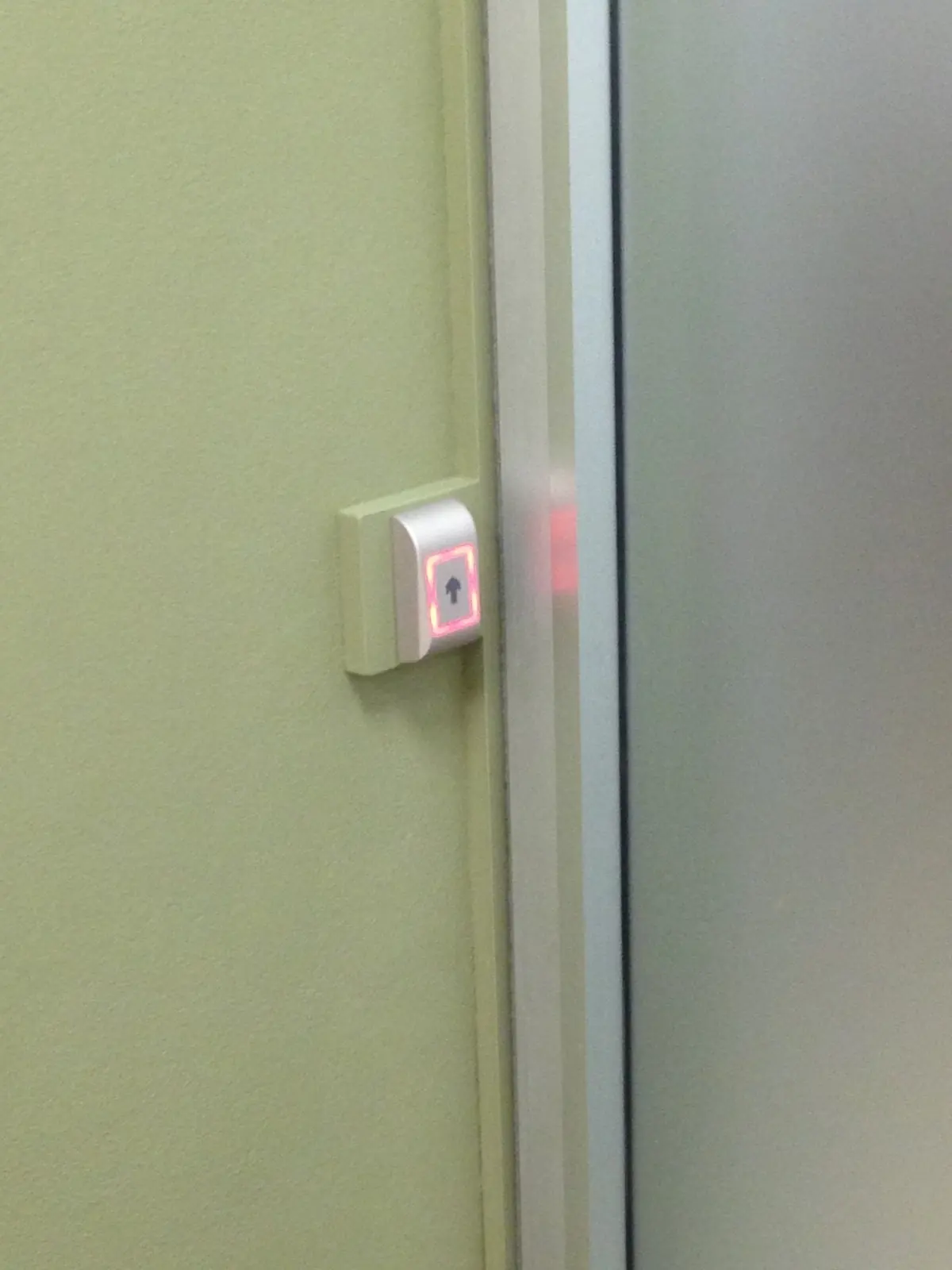 Pulsante di apertura senza contatto accanto a una porta automatica scorrevole